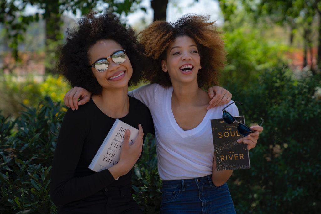 Black female friends laughing and holding books
